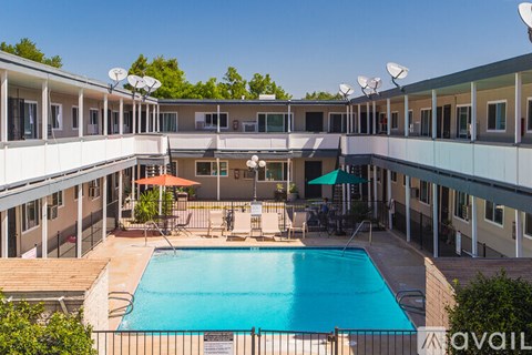 A pool surrounded by a patio and apartment buildings.