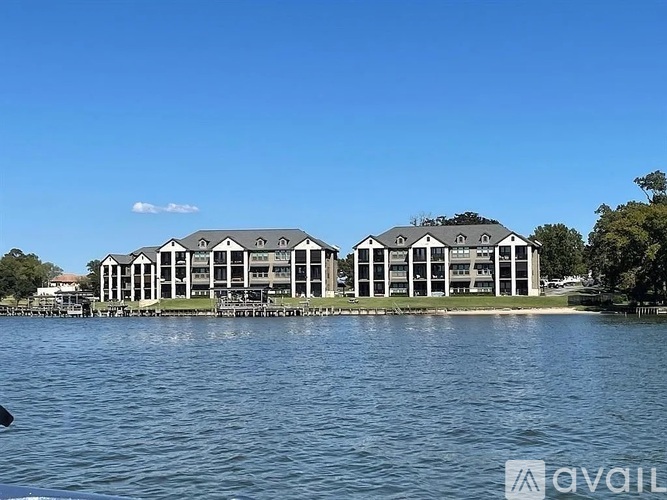 A large white building with a black roof is situated on a small island in the middle of a body of water.
