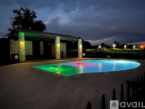 A pool lit up with green, red and blue lights at night.