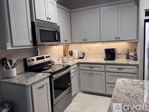 A kitchen with white cabinets and a black microwave above the stove.