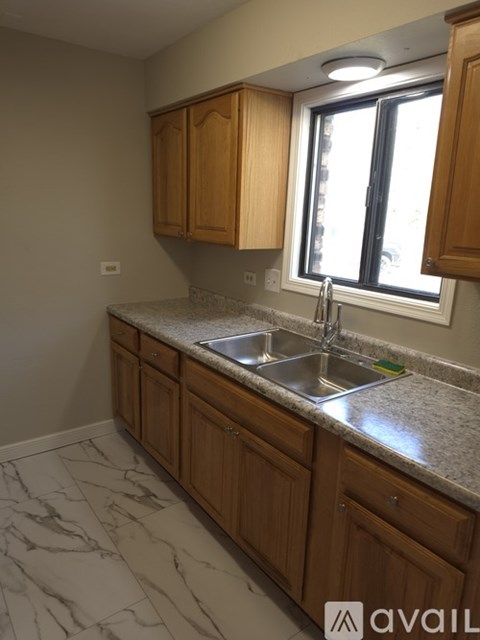 A kitchen with wooden cabinets and marble countertops.