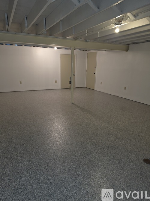 A spacious room with a grey floor and white walls.
