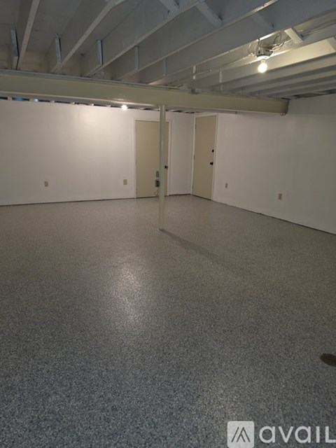 A spacious room with a grey floor and white walls.