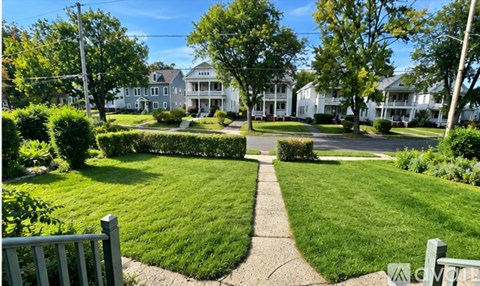 A green lawn with a walkway in the middle and a white house in the background.