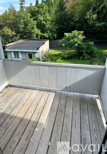 A wooden deck with a house and trees in the background.