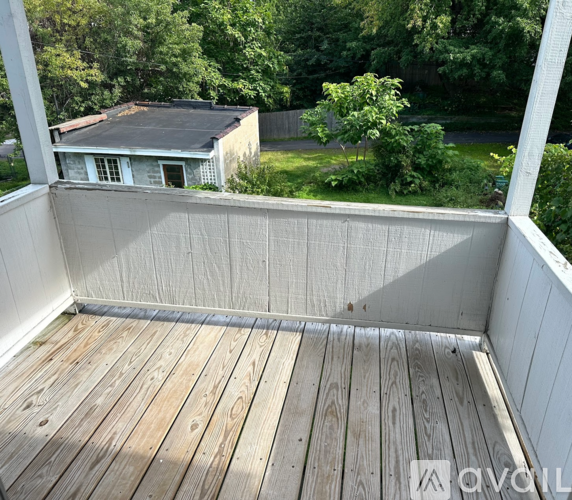 A wooden deck with a white railing and a house in the background.