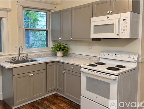 A kitchen with a white stove top oven and a white microwave above it.