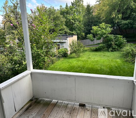 A balcony with a view of a green lawn and trees.