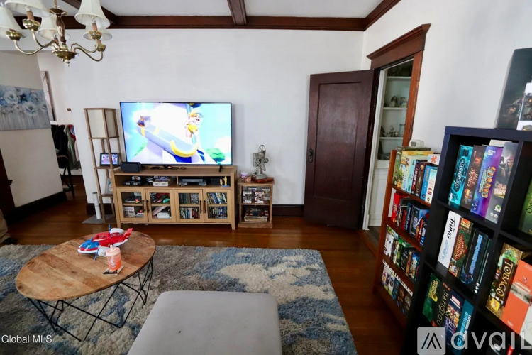 A living room with a television on a stand and a bookshelf filled with books.