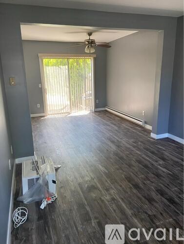 A room with a ceiling fan and sliding glass doors leading to a backyard.