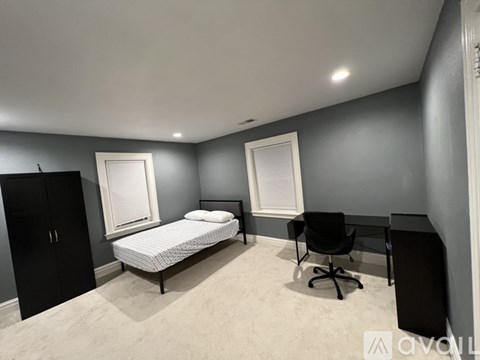 A bedroom with a bed, desk, and chair.
