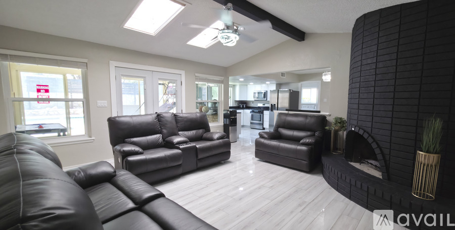 A living room with black leather furniture and a fireplace.