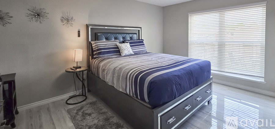 A bedroom with a large bed and a nightstand with a lamp.