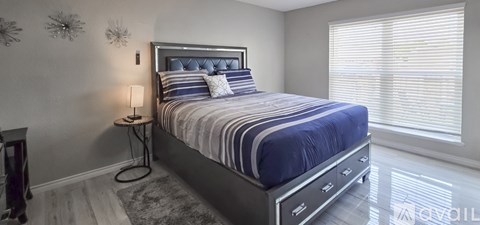 A bedroom with a large bed and a nightstand with a lamp.