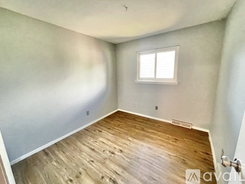 A room with wooden flooring and a window.