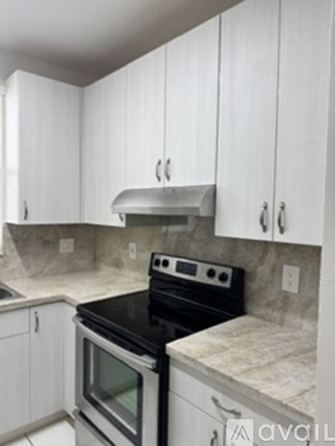 A kitchen with white cabinets and a black stove top oven.