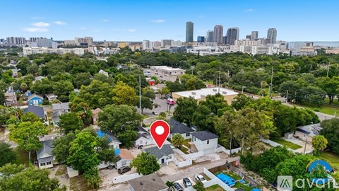 A bird's eye view of a residential area with a swimming pool and a city skyline in the distance.