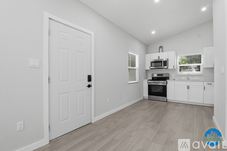 A white door is in a room with a kitchen area in the background.