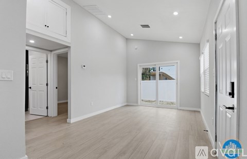 A spacious room with white walls and wooden flooring.