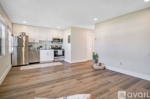 A kitchen with white cabinets and a wooden floor.