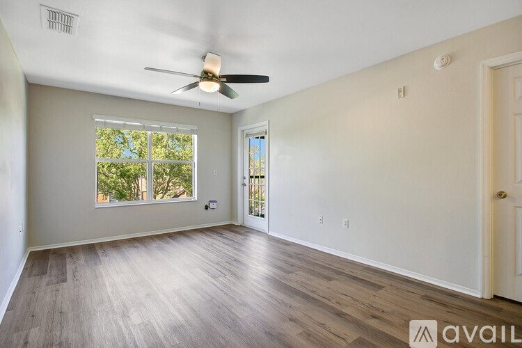 A room with a ceiling fan and a window with a view of trees.