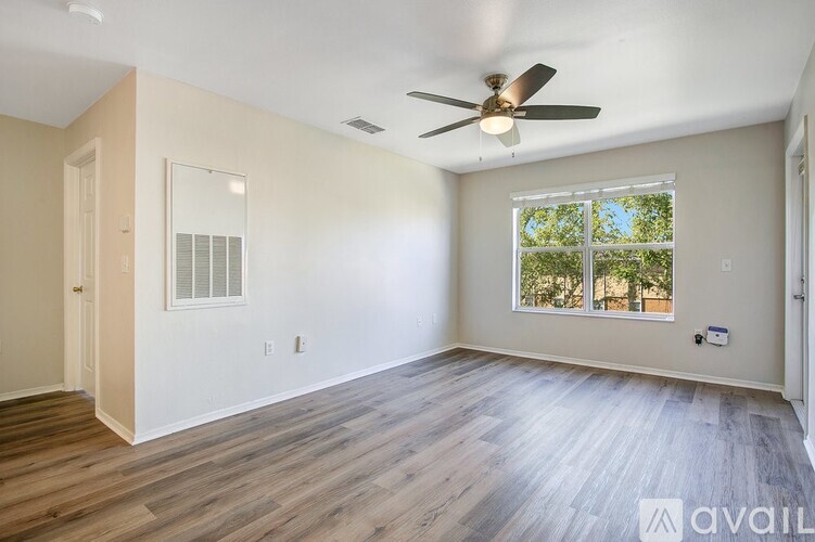 A room with a ceiling fan and a window with a view of trees outside.