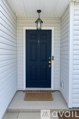 A dark blue door with a brass doorknob and a hanging light fixture.