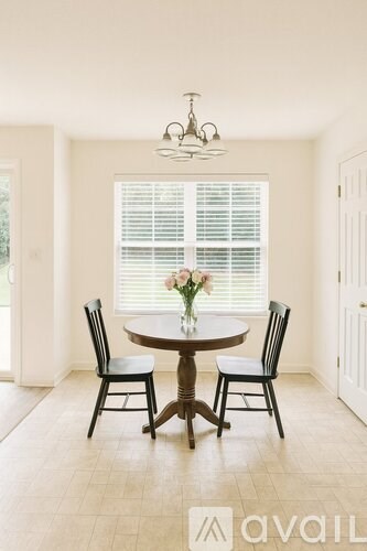 A dining room with a round table and chairs.