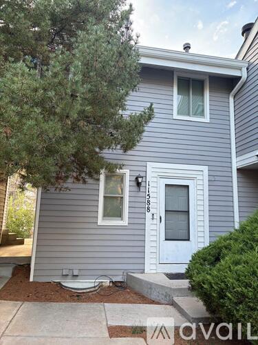 A house with a grey siding and a white door is for sale.