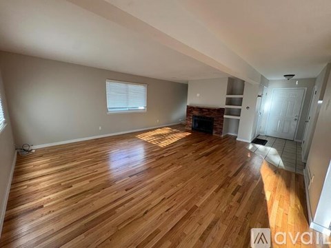 A spacious room with wooden flooring and a fireplace.