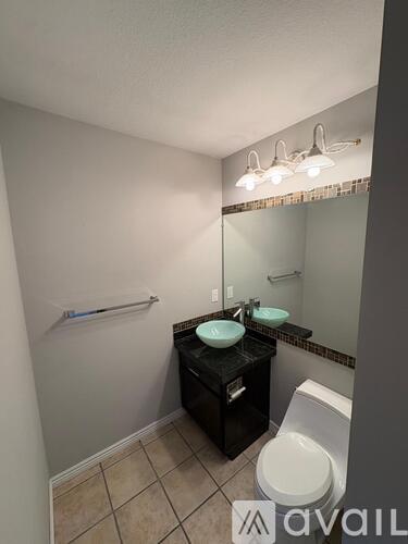 A bathroom with a toilet, sink, and mirror.