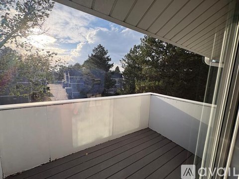 A balcony with a view of trees and a building in the distance.
