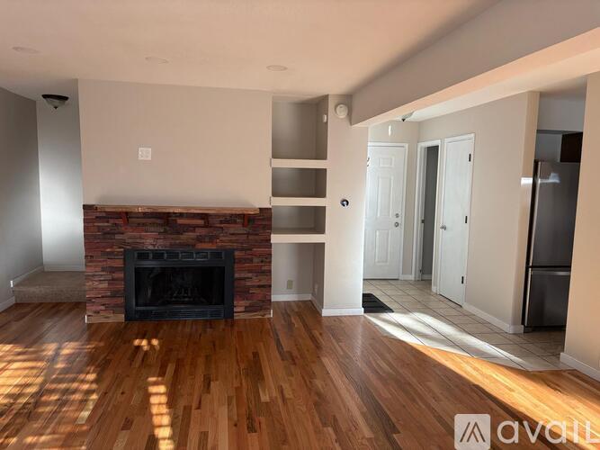 A living room with a fireplace and wooden floors.