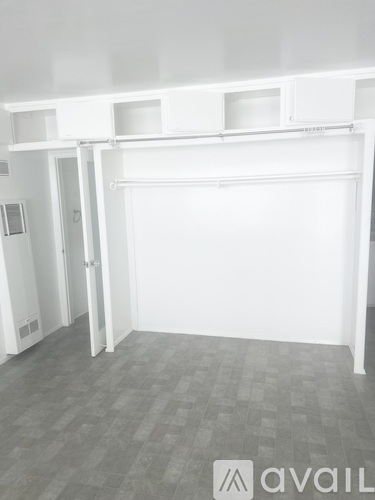 A white room with a grey floor and a white wall with a door on the left.