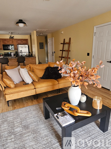 A living room with a brown couch and a coffee table with a vase of flowers on it.