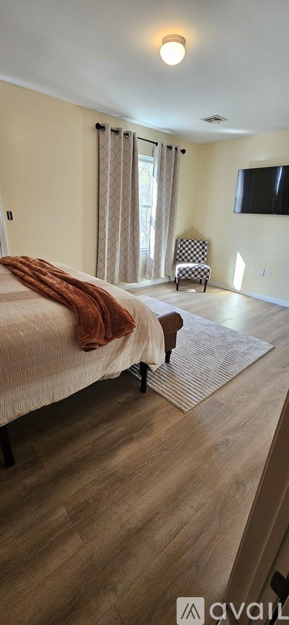 A bedroom with a bed, chair, and television.