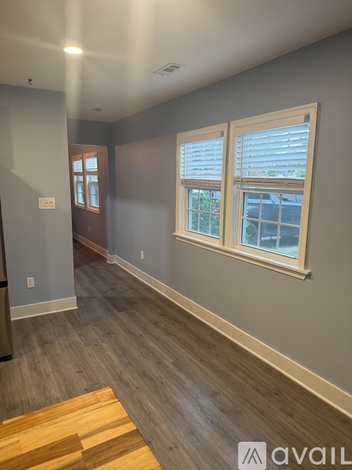 A room with a wooden floor and a window with blinds.