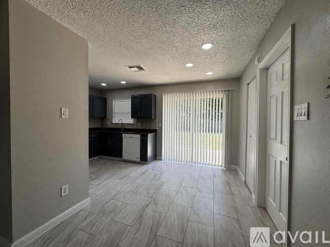 A spacious living room with a kitchen area in the background.