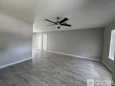 A spacious room with a ceiling fan and tile flooring.