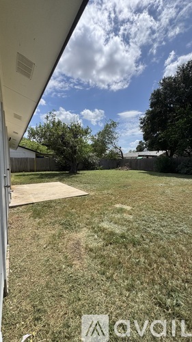 A yard with a white fence and a tree in the background.
