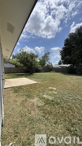 A yard with a white fence and a tree in the background.