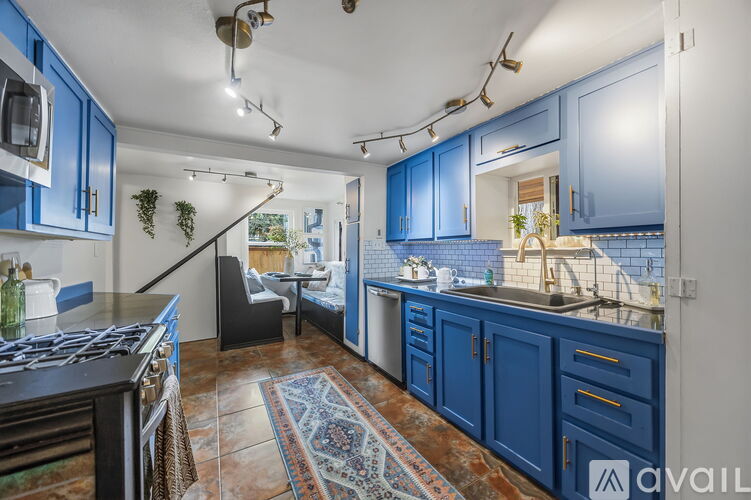A kitchen with blue cabinets and a rug on the floor.