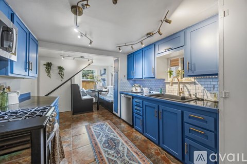 A kitchen with blue cabinets and a rug on the floor.