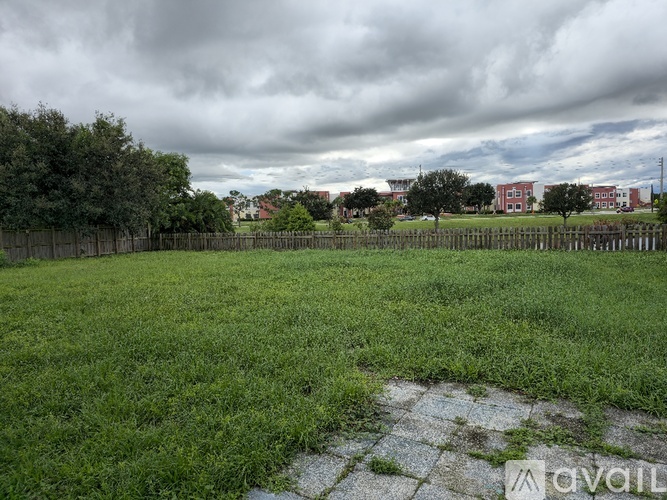 A grassy field with a cloudy sky and buildings in the distance.