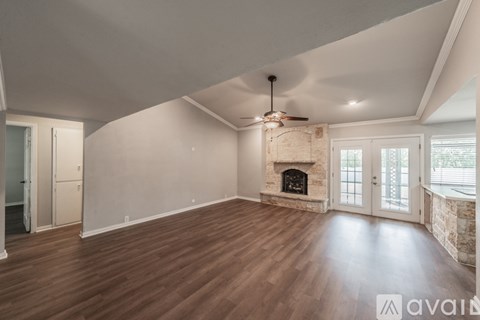 A spacious living room with wood flooring and a fireplace.