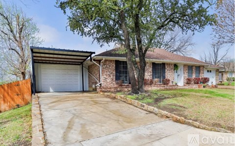A house with a garage and a tree in front.