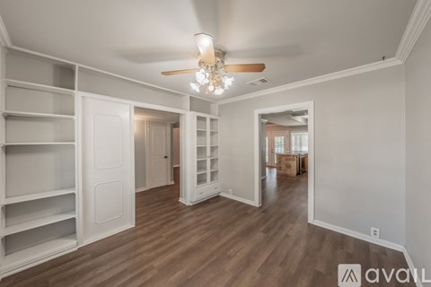 A spacious room with a ceiling fan and built-in shelves.