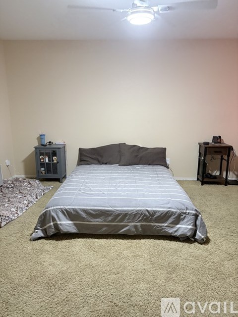 A bedroom with a bed, a nightstand, and a small table.