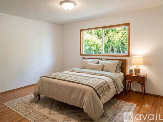 A bedroom with a large bed and a window overlooking a green area.