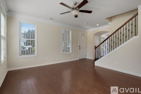 A spacious room with a ceiling fan and wooden flooring.